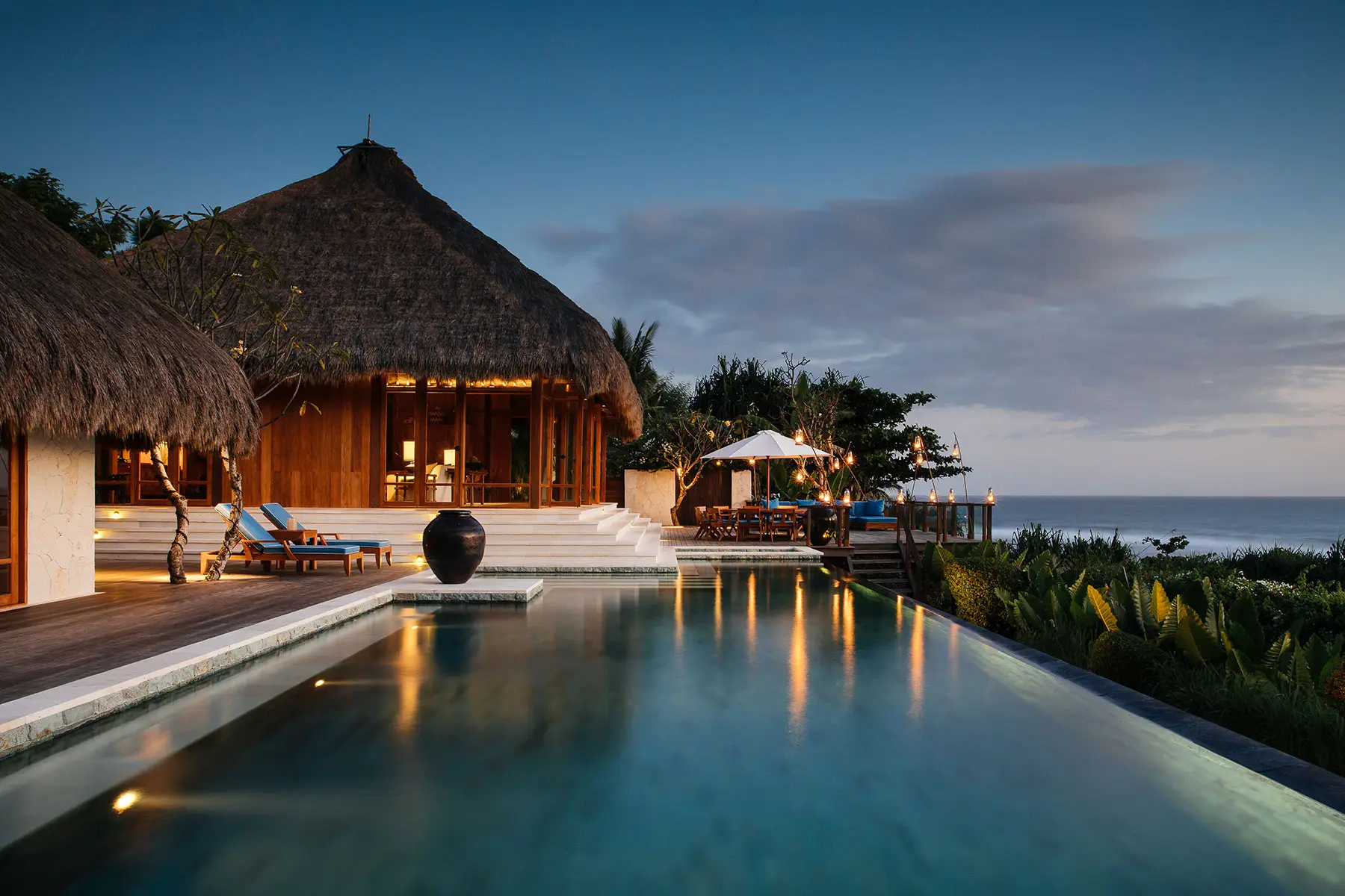 Private NIHI Sumba villa glowing beside an infinity pool at sunset